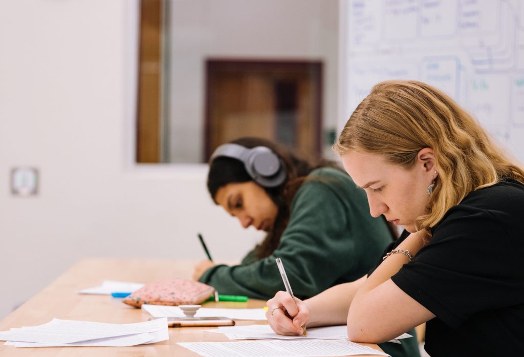 A male and female student doing their work in a school classroom.