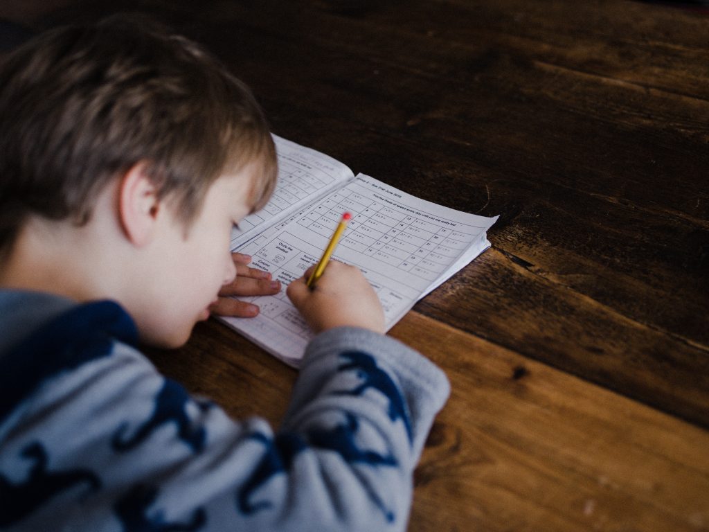 Elementary school boy doing a math worksheet at his desk.