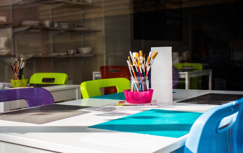 Elementary school classroom with colorful blue, purple and pink desk designs.