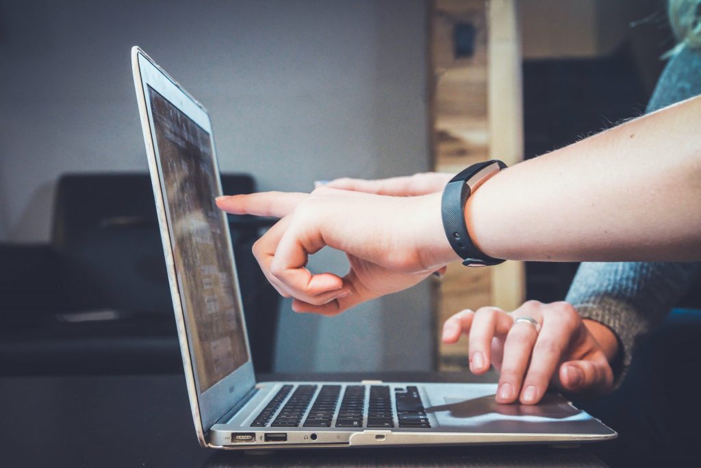 Two kids pointing at a laptop referencing their online schooling.