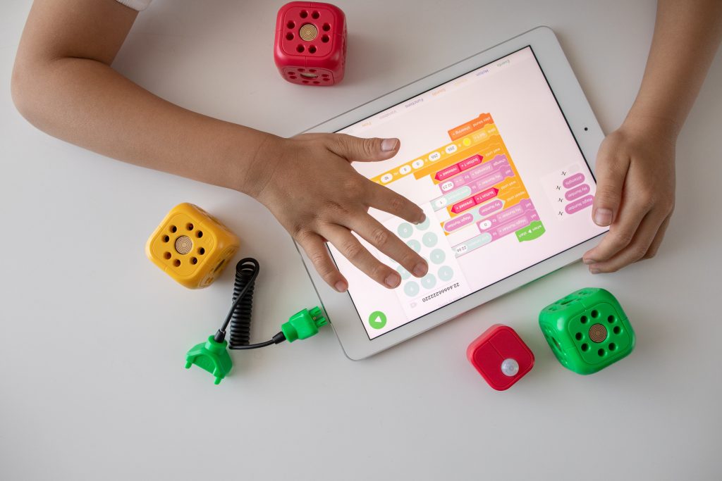 Young child playing on an iPad with toys around them.