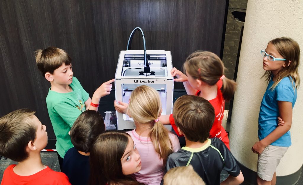 group of students gathered around a 3d printer