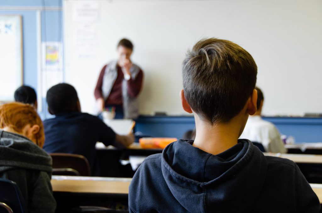 Young boy sitting in the back of a classroom