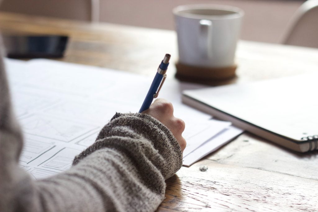 Student writing at a desk